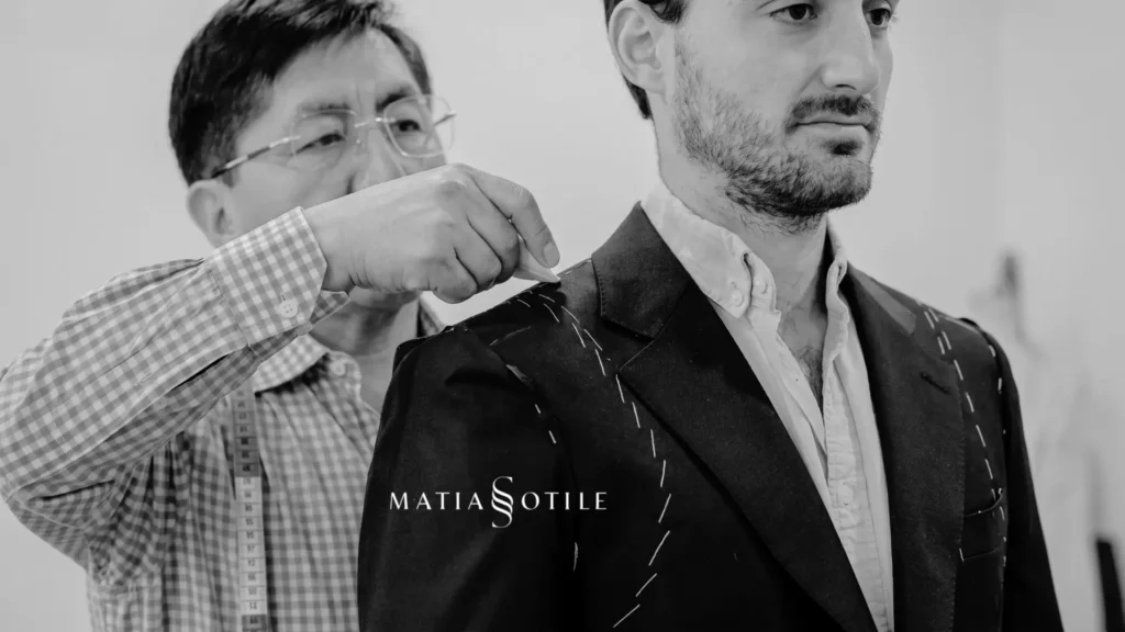 Sastre realizando ajustes de hombro y solapa en la prueba de un traje a medida artesanal